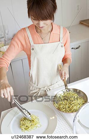 Stock Photo - Young woman serving pasta. Fotosearch