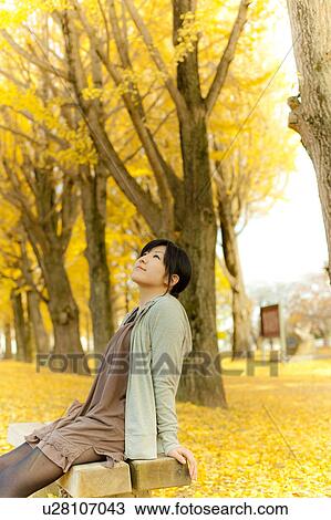 Young woman sitting on park bench View Large Photo Image Stock Image - Young woman sitting on park bench. Fotosearch