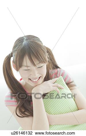 Stock Image - Young woman sitting on sofa. Fotosearch