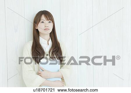 Young woman standing by wall View Large Photo Image Stock Image - Young woman standing by wall. Fotosearch