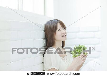 Stock Photograph - Young woman with houseplant. Fotosearch