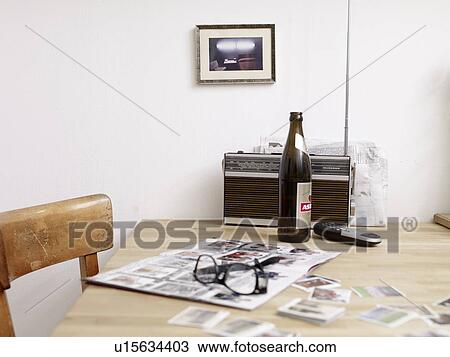 Stock Image - Beer bottle, eyeglasses and album with soccer collector cards on table. Fotosearch