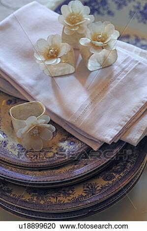 Stock Image - Blossoms and napkins on stack of plates. Fotosearch