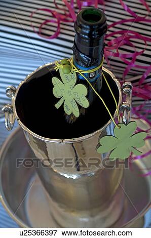 Stock Photo - Bottle of champagne decorated with four leaf clover in champagne bucket. Fotosearch