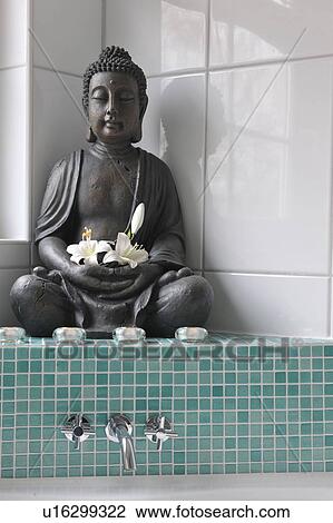 Stock Image - Buddha figurine with blossoms. Fotosearch
