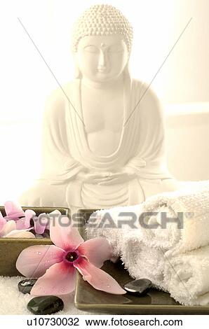 Stock Image - Buddha statuette with blossoms and hematite. Fotosearch