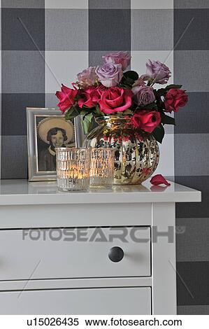 Stock Photography - Bunch of roses, photograph and candles on dresser. Fotosearch