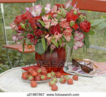 Stock Photo - Bunch of summer flowers and strawberries on garden table. Fotosearch