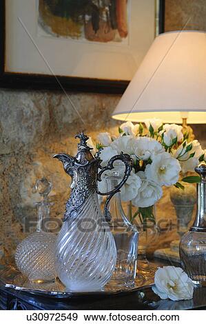 Stock Photo - Carafe, bunch of flowers and lamp on dresser. Fotosearch