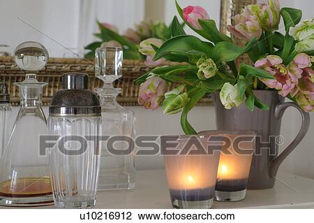 Stock Image - Carafe, burning candles and bunch of flowers. Fotosearch
