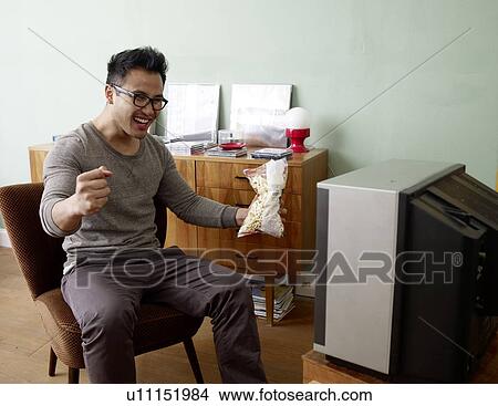 Cheering man watching TV View Large Photo Image Picture - Cheering man watching TV. Fotosearch
