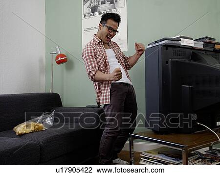 Cheering man watching TV View Large Photo Image Stock Image - Cheering man watching TV. Fotosearch