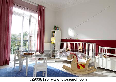 Stock Image - Childrens room with rocking dragon and crib. Fotosearch