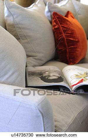 Stock Image - Coffee table book and cushions on couch. Fotosearch