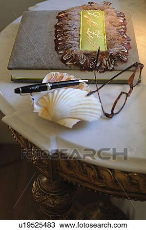 Eyeglasses, decorative seashell, pen and book on table View Large Photo Image Stock Image - Eyeglasses, decorative seashell, pen and book on table. Fotosearch