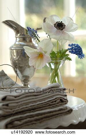 Stock Image - Flowers, pile of cloths and silver jug. Fotosearch
