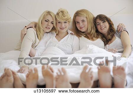 Four young women lying in bed View Large Photo Image Stock Photo - Four young women lying in bed. Fotosearch