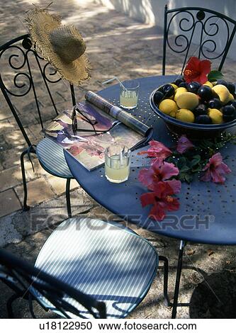 Stock Image - Garden table with hibiscus flowers and fruit bowl. Fotosearch