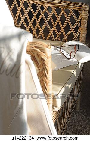 Picture - Glasses and book on wicker chair. Fotosearch