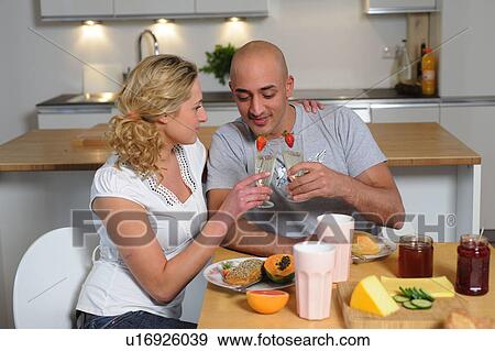 Stock Photo - Happy couple clinking champagne glasses in kitchen. Fotosearch