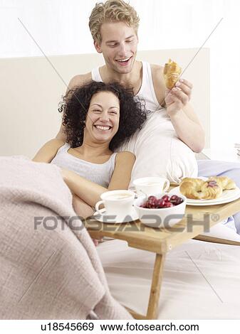 Stock Photo - Happy couple having breakfast in bed. Fotosearch