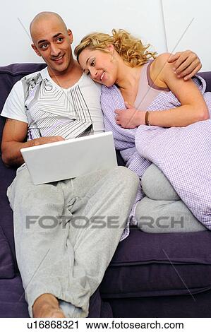 Happy couple on couch using laptop View Large Photo Image Stock Image - Happy couple on couch using laptop. Fotosearch