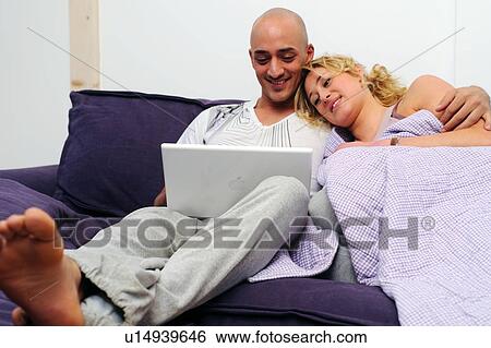 Happy couple on couch using laptop View Large Photo Image Stock Photograph - Happy couple on couch using laptop. Fotosearch