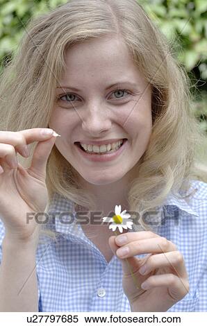 Stock Photography - Happy young woman plucking petals from daisy. Fotosearch