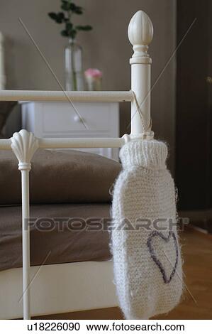 Stock Image - Hot-water bottle leaning against bed. Fotosearch