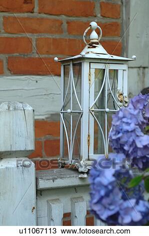 Stock Image - Hydrangea and lantern in front of timber-framed house. Fotosearch