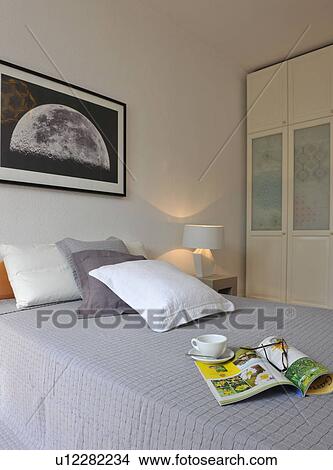 Picture - Magazine, eyeglasses and cup of coffee on bed. Fotosearch