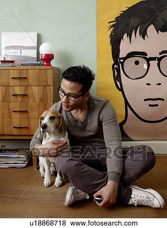 Man caressing dog at home View Large Photo Image Stock Photo - Man caressing dog at home. Fotosearch