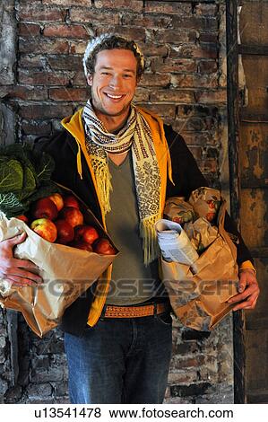 Man carrying shopping bags with produce View Large Photo Image Stock Photo - Man carrying shopping bags with produce. Fotosearch