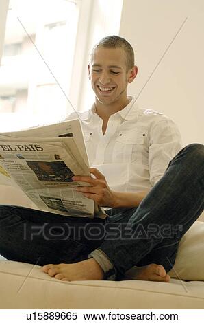 Stock Photography - Man reading newspaper on couch. Fotosearch