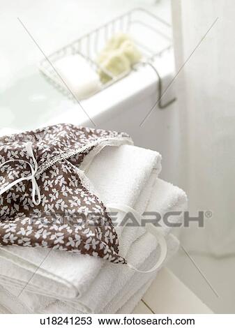 Stock Image - Nightdress on pile of towels in bathroom. Fotosearch