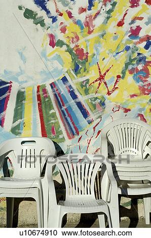 Plastic chairs in front of painted building facade View Large Photo Image Stock Image - Plastic chairs in front of painted building facade. Fotosearch