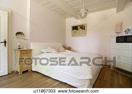 Stock Image - Rustic bedroom with tiled stove. Fotosearch