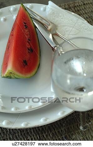 Slice of watermelon on plate and glass of water View Large Photo Image Stock Photo - Slice of watermelon on plate and glass of water. Fotosearch