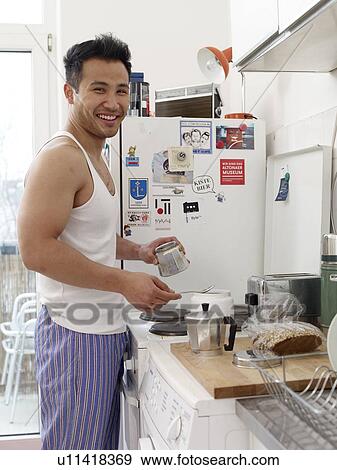Smiling man in kitchen making coffee View Large Photo Image Stock Photo - Smiling man in kitchen making coffee. Fotosearch