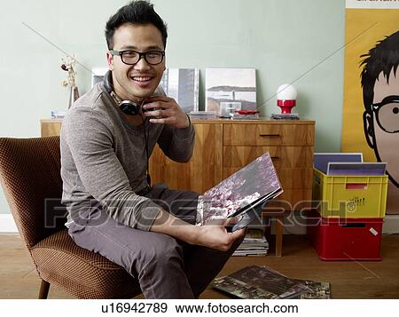 Stock Photo - Smiling man with headphones holding record. Fotosearch