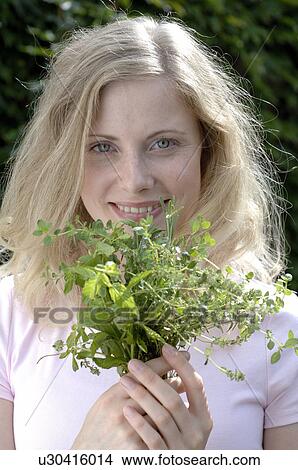 Picture - Smiling woman holding herbs. Fotosearch