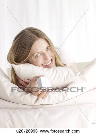 Stock Image - Smiling woman in bed. Fotosearch