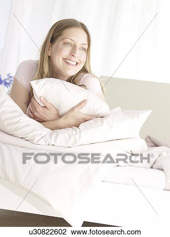 Stock Image - Smiling woman in bed. Fotosearch