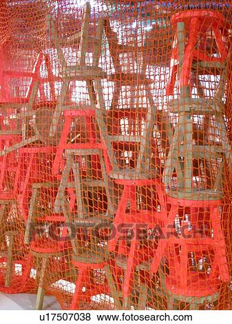Stock Photo - Stack of stools behind net. Fotosearch
