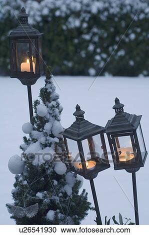 Stock Image - Storm lanterns in garden in winter. Fotosearch