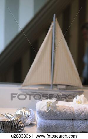 Stock Image - Towels, blossoms and model boat. Fotosearch