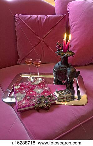 Stock Photo - Tray with liqueur, book and candles on pink couch. Fotosearch