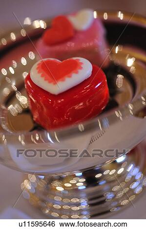 Stock Photograph - Two heart-shaped chocolate candies in silver bowl. Fotosearch
