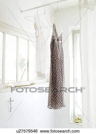 Stock Photograph - Two nightdresses hanging in bathroom. Fotosearch