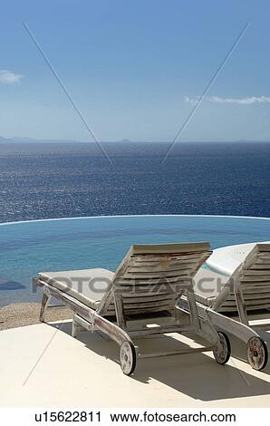 Two sun loungers by the poolside above the ocean View Large Photo Image Stock Image - Two sun loungers by the poolside above the ocean. Fotosearch